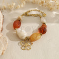 Pulsera con cuentas naranjas y blancas y colgante de flor